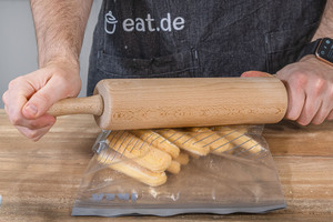 Löffelbiskuits in einen Gefrierbeutel geben und mit dem Nudelholz zerbröseln