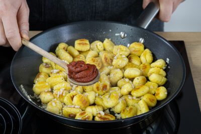Tomatenmark zu den Gnocchi geben