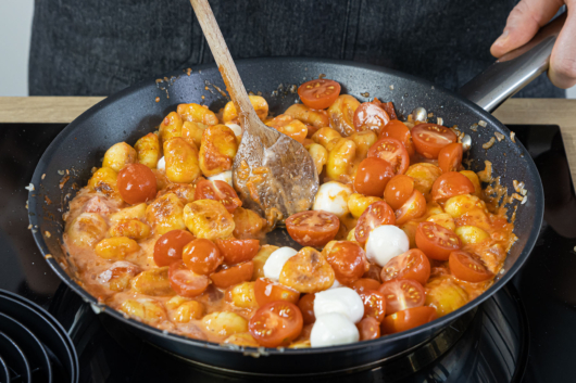 Mozzarella und Tomatensauce zu den Gnocchi geben