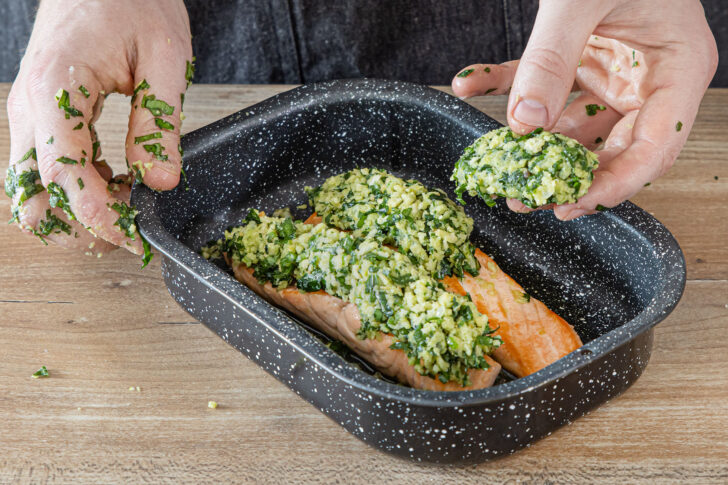 Bärlauchs Kruste auf dem Lachs verteilen