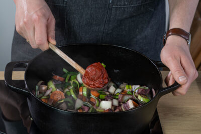 Tomatenmark zum Gemüse geben