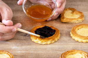 Rand des Ochsenaugen-Gebäcks mit Aprikosenmarmelade bestreichen