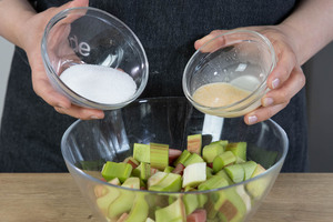Zucker und Orangensaft-Gemisch zum Rhabarber geben
