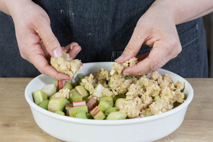 Streusel auf dem Rhabarber verteilen