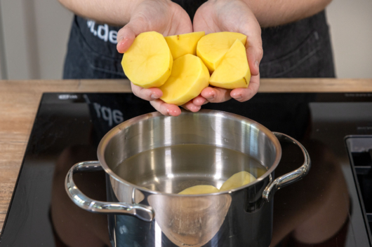 Kartoffeln in einen Topf mit Wasser geben