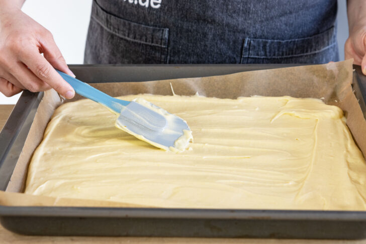 Teig als Boden für Spiegeleikuchen auf Backblech verstreichen