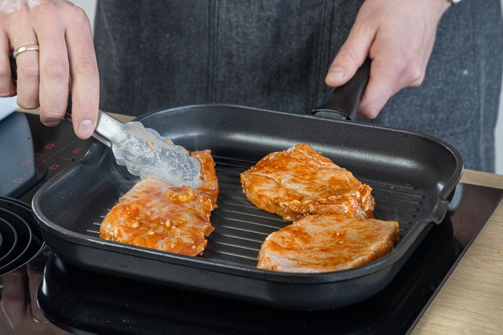 Marinierte Schweinerückensteaks in die Pfanne geben