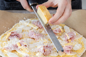 Parmesan über Spargelpizza mit Schinken und Sauce Hollandaise reiben