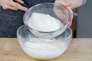 Mehl, Backpulver und Puddingpulver in Schüssel sieben