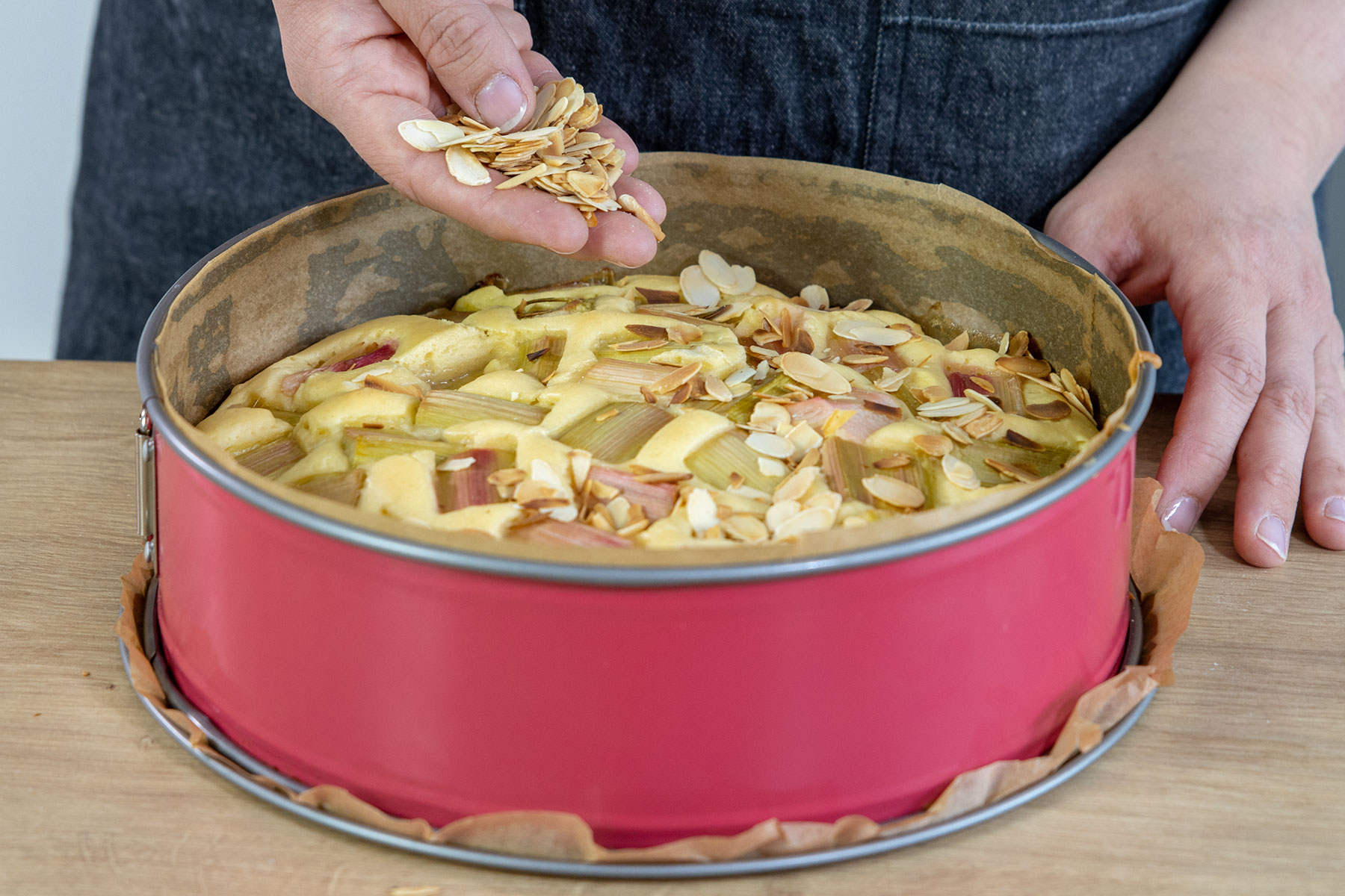 Veganen Rhabarberkuchen ohne Ei mit gerösteten Mandeln bestreuen