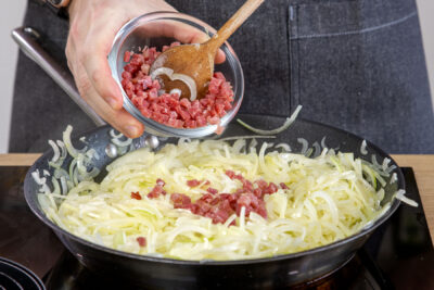 Schinkenwürfel zu den Zwiebeln geben
