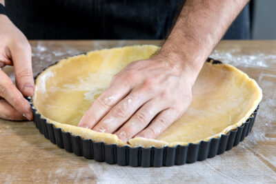 Mürbeteig in Tarteform verteilen