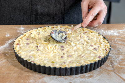 Füllung für Zwiebelkuchen auf den Mürbeteig geben