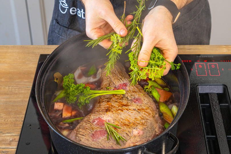 Fleisch und Kräuter in den Bräter geben