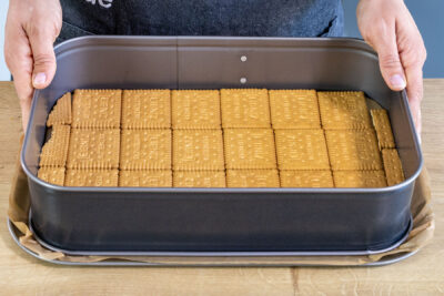 Eine Schicht Butterkekse als Boden in eine Form legen