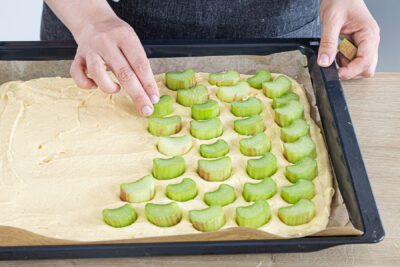 Rhabarberstücken auf dem Kuchenteig verteilen