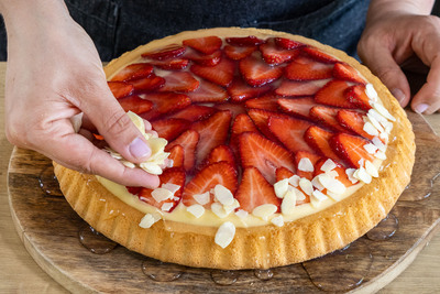 Mandelsplitter auf den Erdbeerkuchen mit Vanillepudding streuen