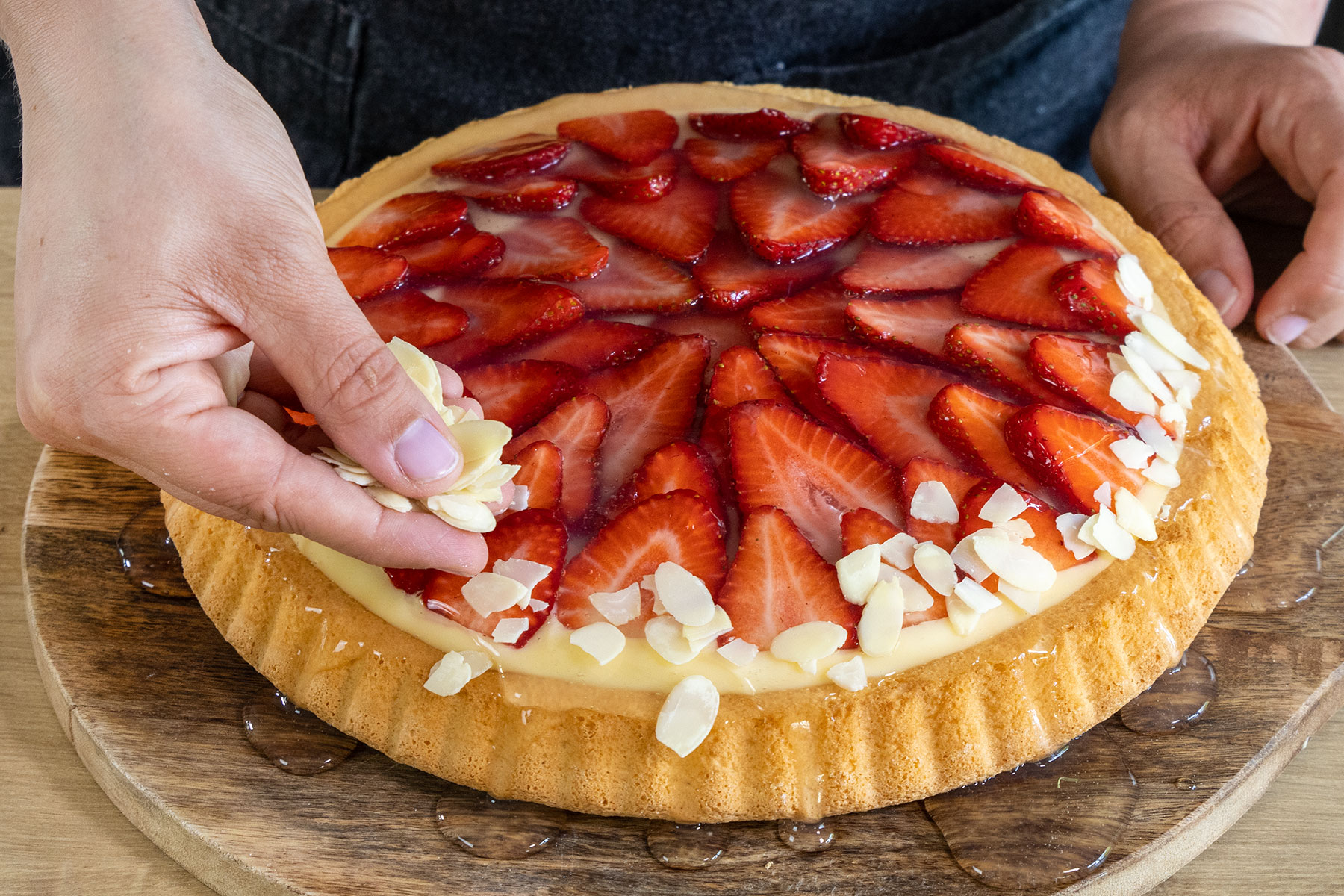 Mandelsplitter auf den Erdbeerkuchen mit Vanillepudding streuen