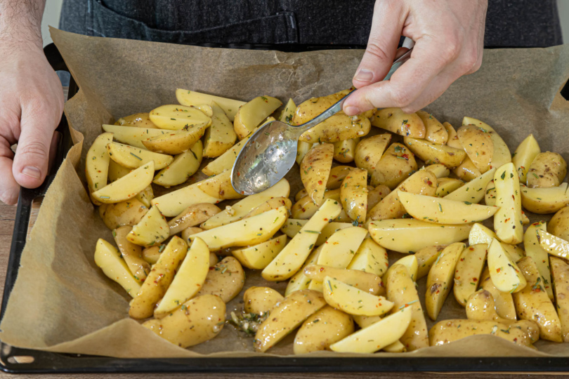 Kartoffelspalten auf dem Blech verteilen und im Ofen garen