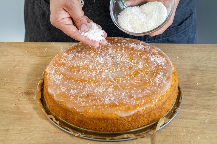 Kokosstreusel auf den Kokoskuchen ohne Buttermilch streuen