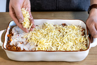Käse auf der Bolognese-Lasagne verteilen