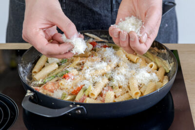 Parmesan zur Pasta mit grünem Spargel geben