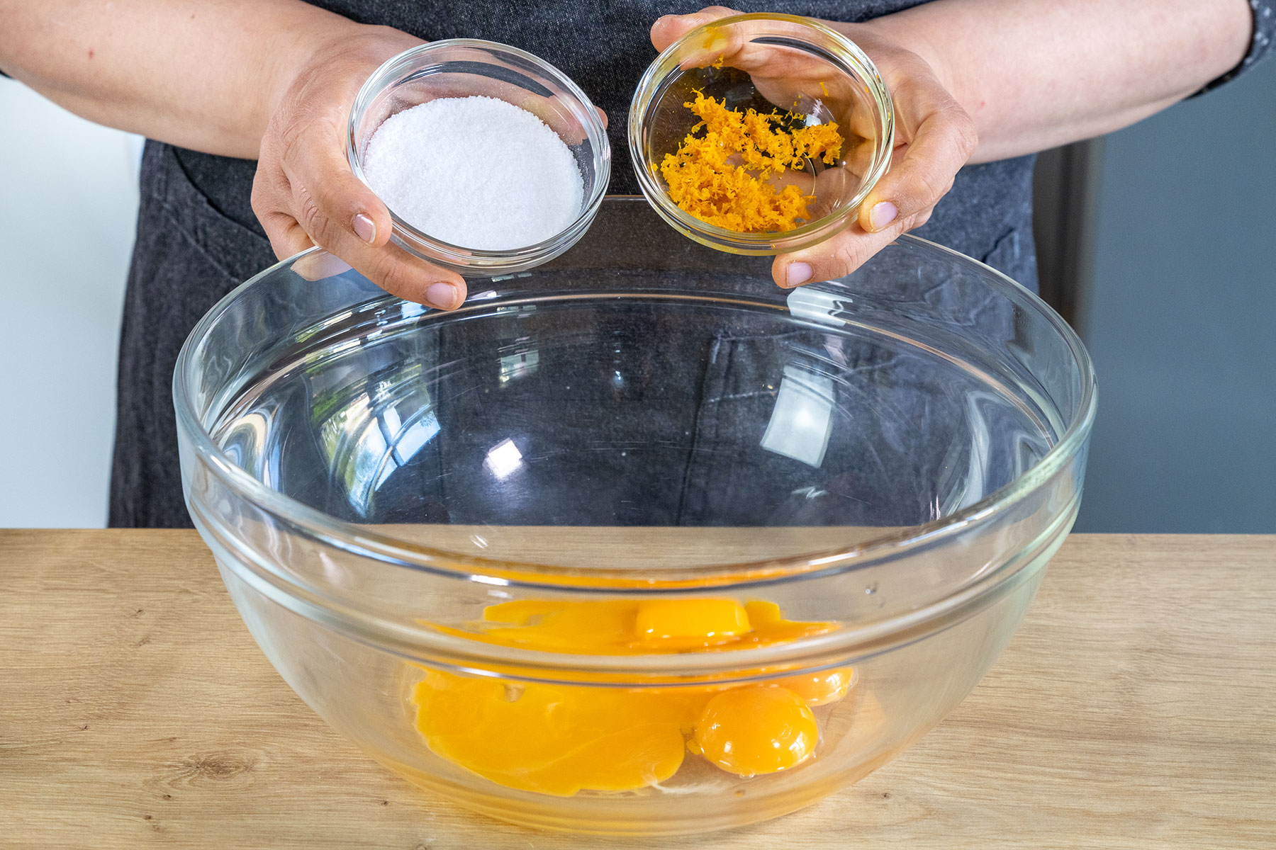 Zucker, Vanillezucker und Orangenschalenabrieb zum Eigelb geben