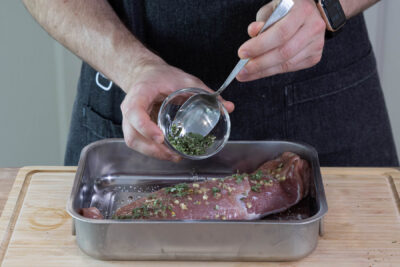 Kräuter über das Fleisch streuen