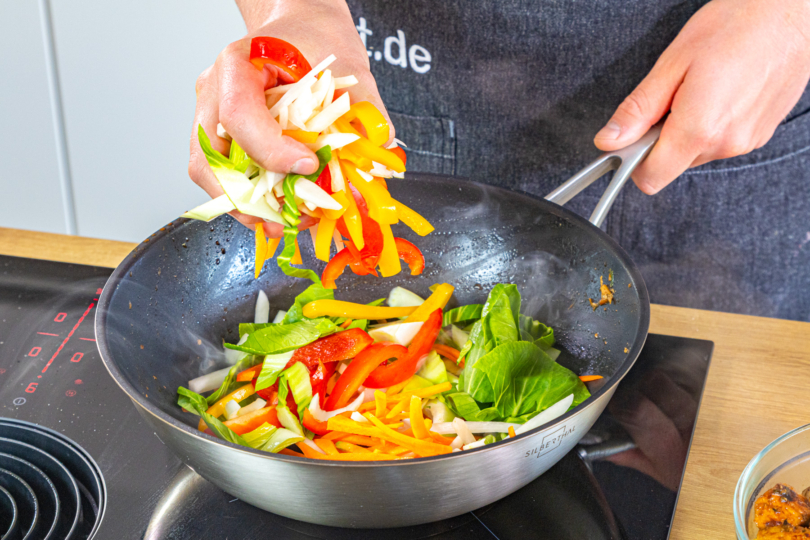 Gemüse in den Wok geben
