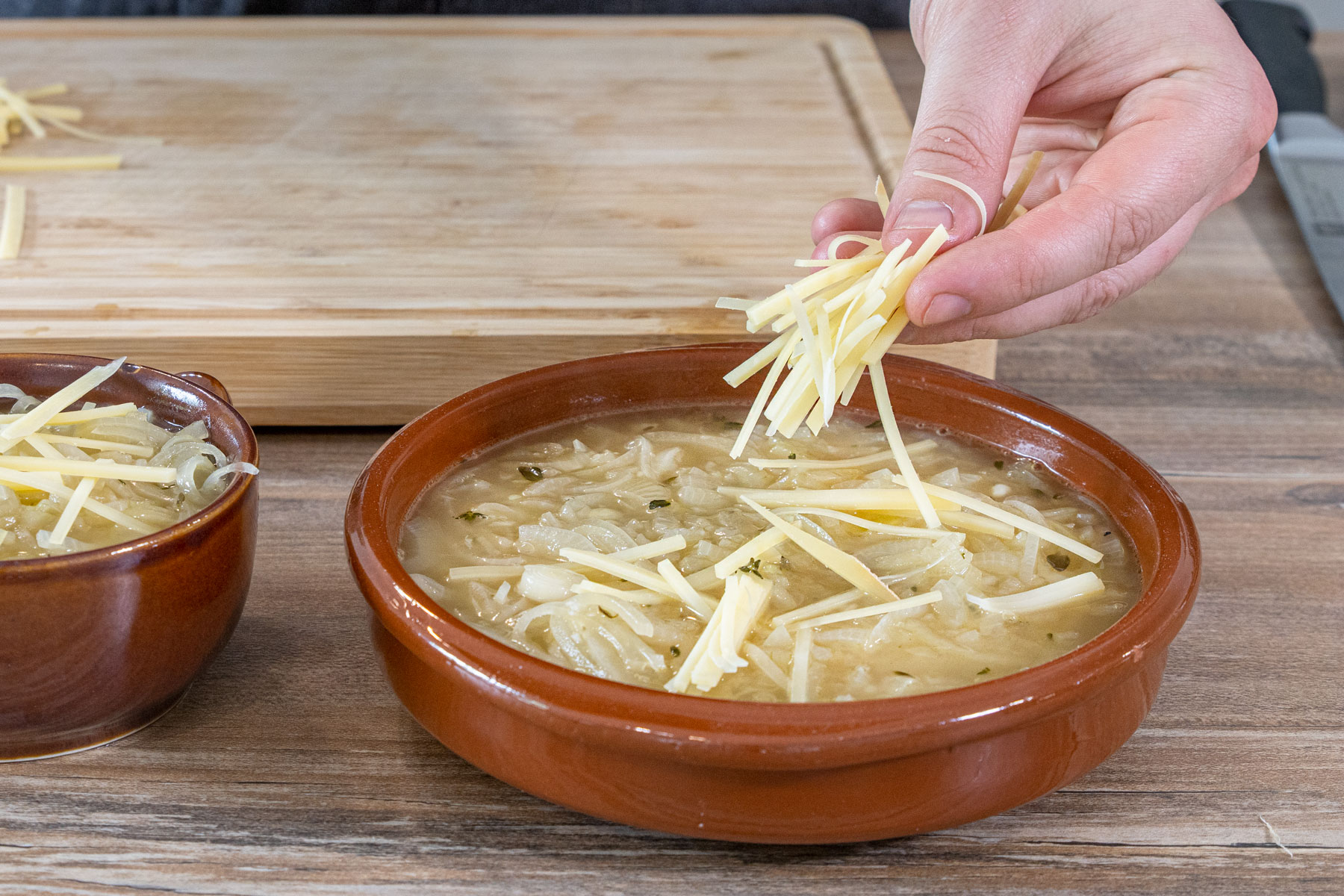 Käse auf die Französische Zwiebelsuppe geben