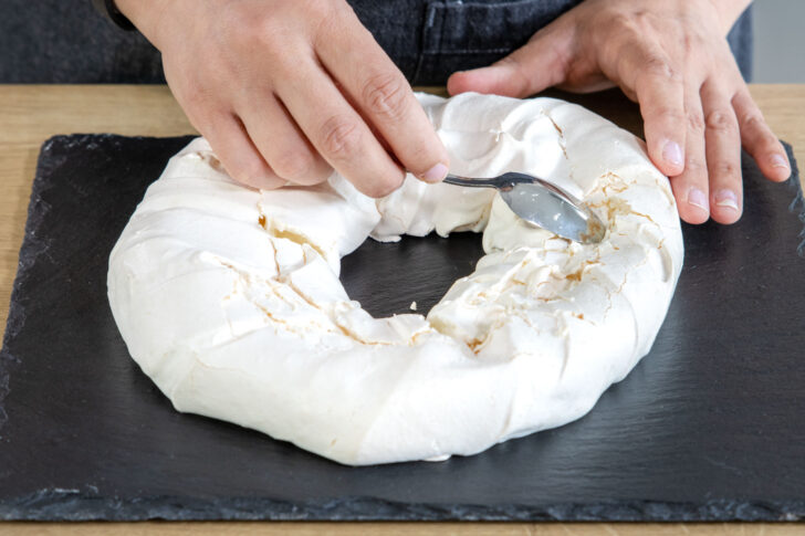 Klassische Pavlova mit einem Löfel aufbrechen