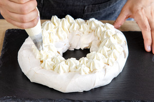 Creme auf die klassische Pawlova spritzen