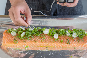 Frühlingszwiebeln auf dem Lachs verteilen