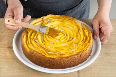 Mangokuchen mit Aprikosenmarmelade einstreichen