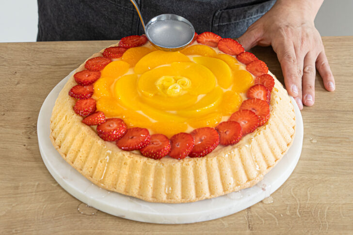 Tortenguss über das Obst geben