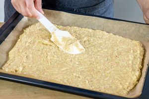 Teig für den saftigen Zucchinikuchen auf dem Backblech verstreichen
