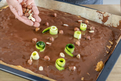 Saftigen Zucchinikuchen mit Haselnüssen und Zucchiniröllchen dekorieren