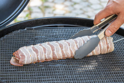 Schweinefilet im Speckmantel auf den Grill legen