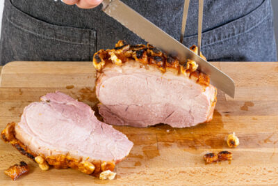 Schweinekrustenbraten aus dem Backofen in Scheiben schneiden
