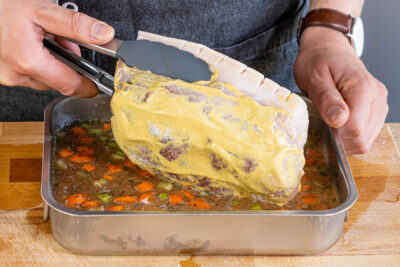 Schweinekrustenbraten in den Fond legen und im Backofen garen