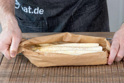 Spargel in Backpapier legen