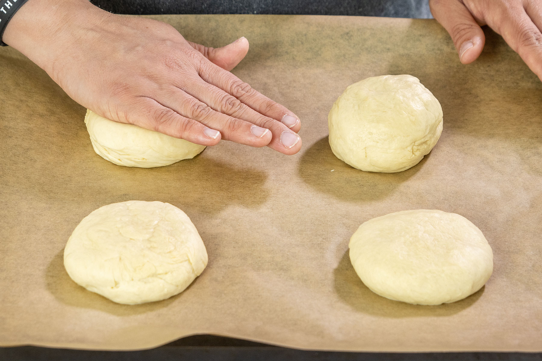 Teigkucgeln zu Burger Buns plattdrücken