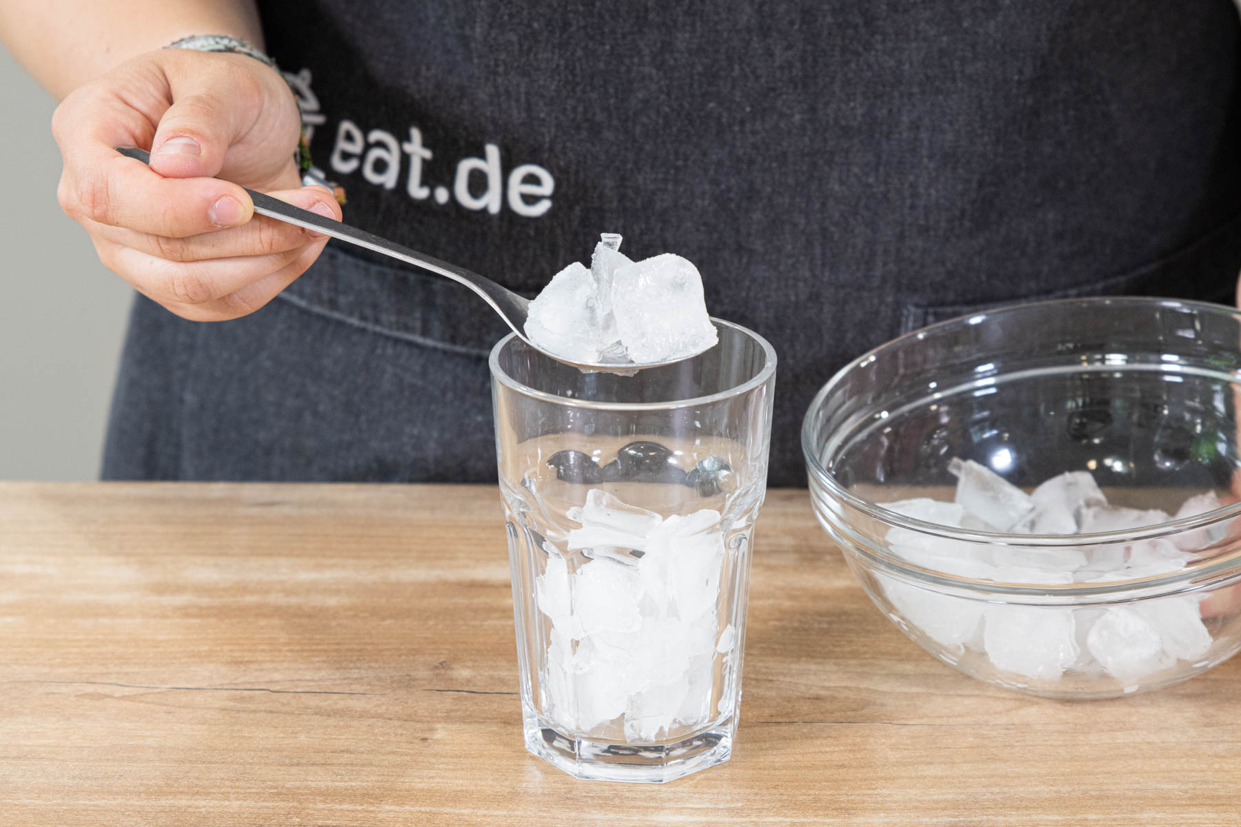 Eiswürfel in ein Glas geben