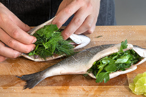 Dorade mit Kräutern, Schalotten und Liemttescheiben füllen