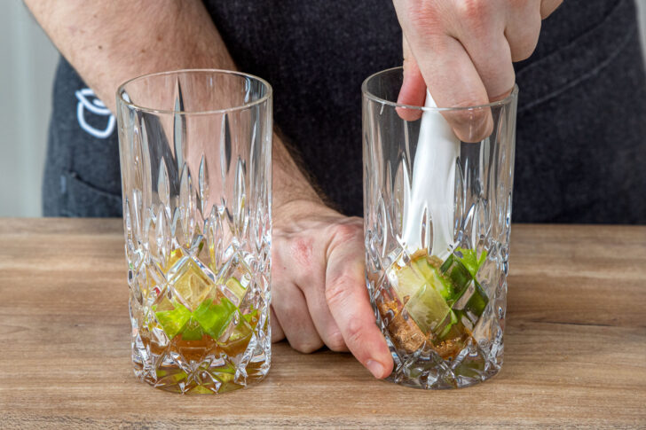 Limetten und Zucker mit dem Stößel zerdrücken