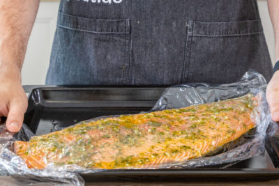 Lachs mit mediterraner Marinade mit Frischhaltefolie bedecken