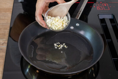 Knoblauch und Zwiebel in Pfanne geben