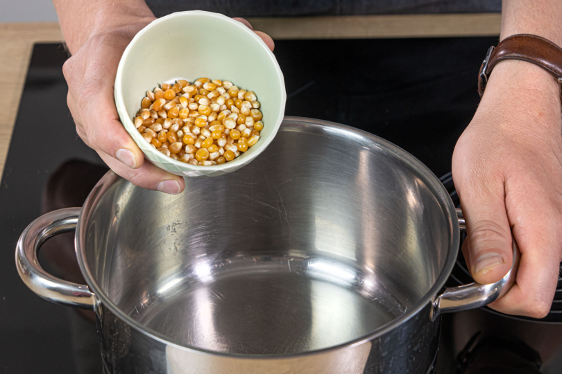 Popcorn Mais ins heiße Öl geben