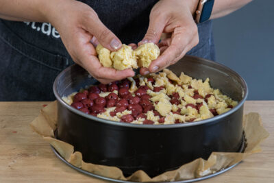 Streusel auf dem Kirschkuchen verteilen
