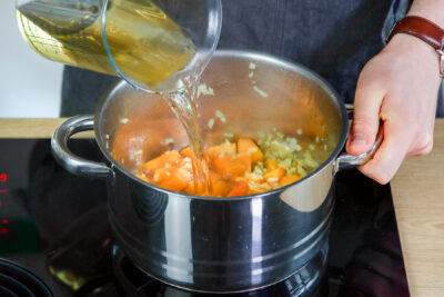 Kürbis-Ingwer-Kokos-Suppe mit Gemüsebrühe ablöschen